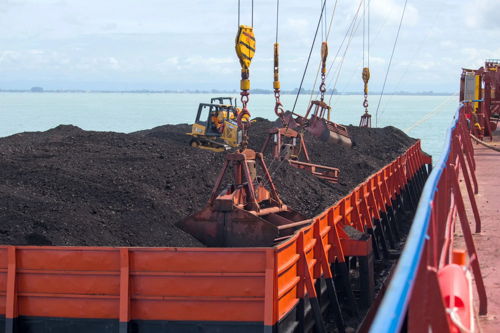Grabs working a coal barge alongside a cargo ship