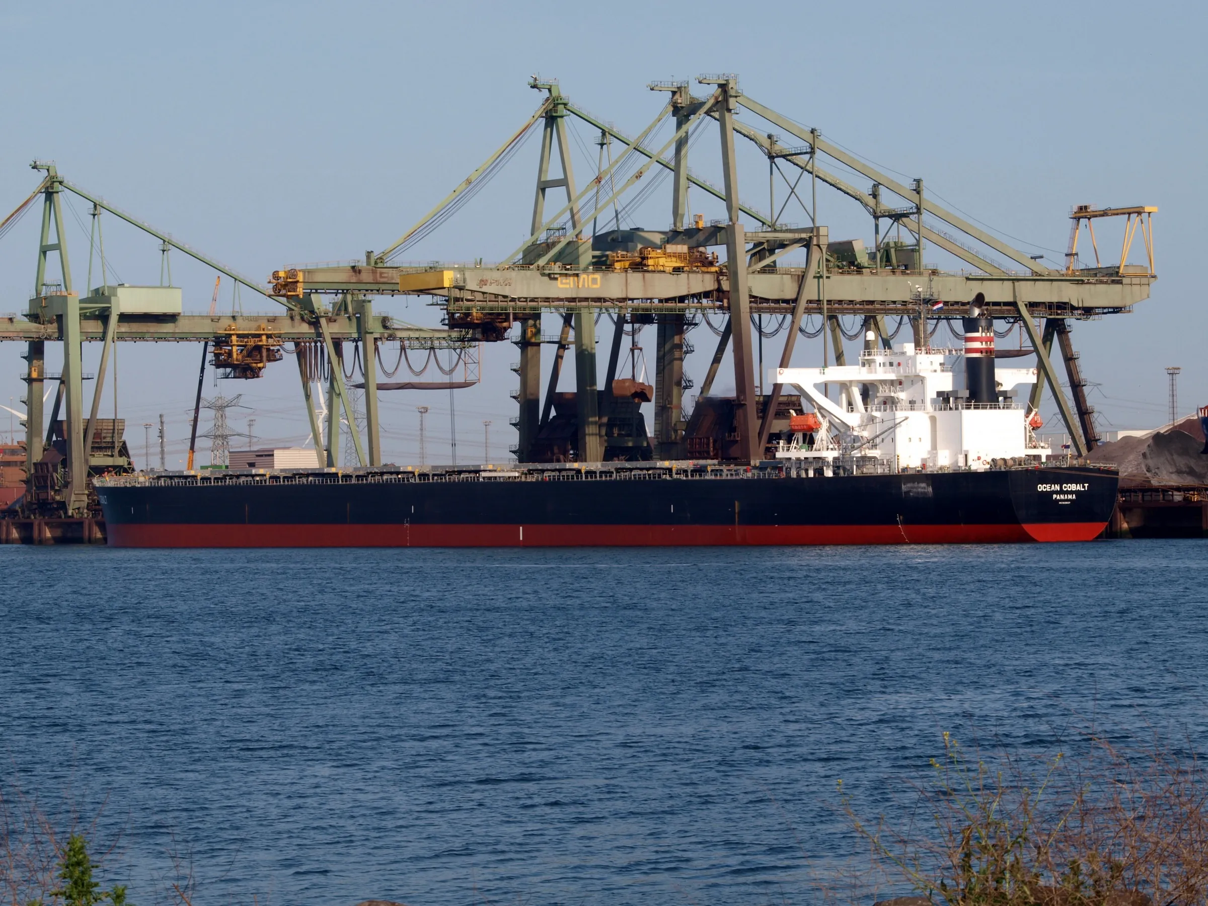 Bulk carrier alongside a dry-bulk berth with unloading cranes